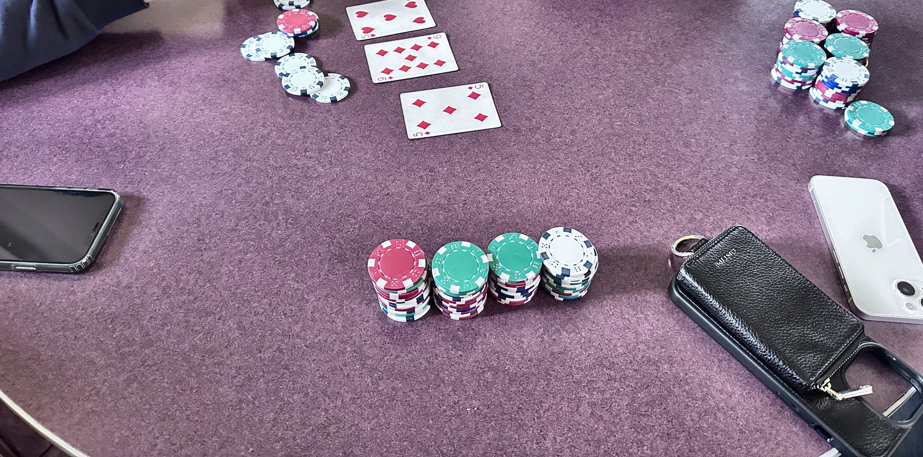 A round table with playing cards dealt out and stacks of poker chips