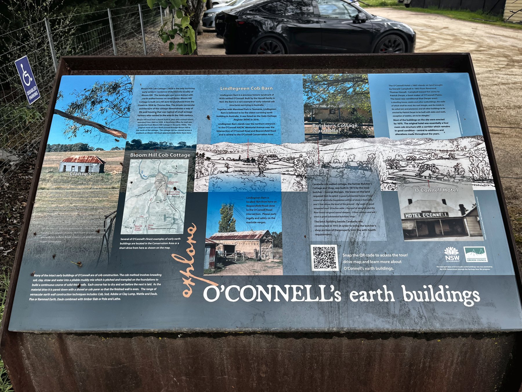 A roadside interpretive panel headed O&rsquo;Connell&rsquo;s earth buildings, with photographs and a map of the village