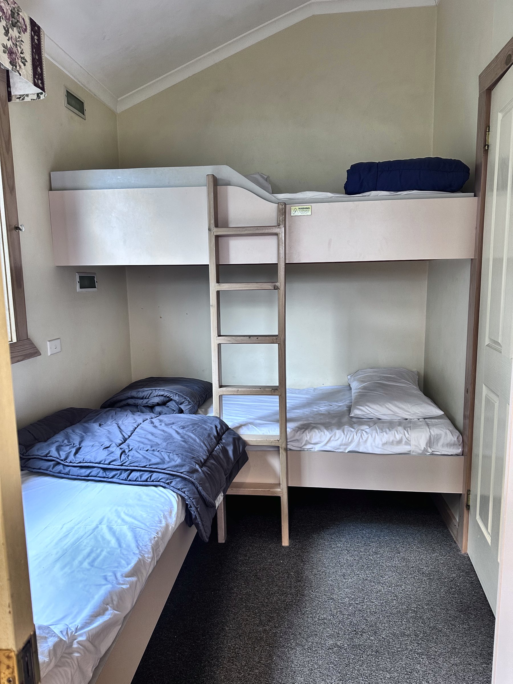 A second bedroom with a timber bunk bed and a separate single bed, all made up