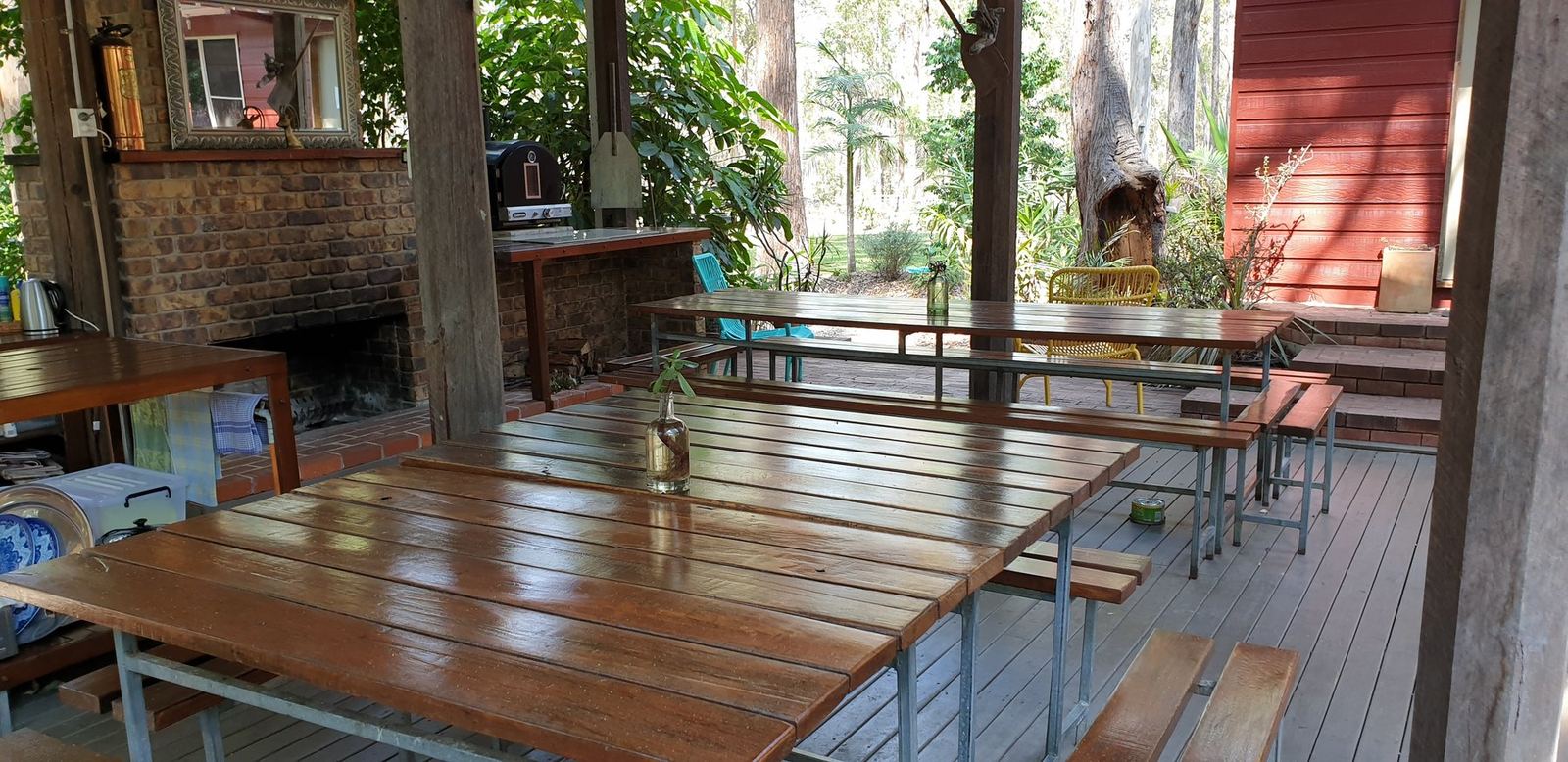 Long timber tables and bench seats under the same roof, set up for a group to eat together