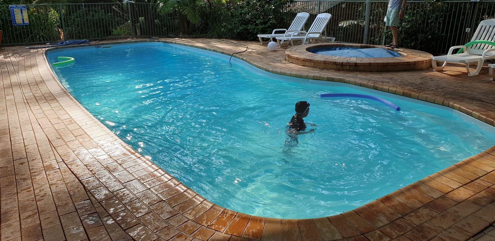 The pool the following morning with the deck chairs out and one person swimming