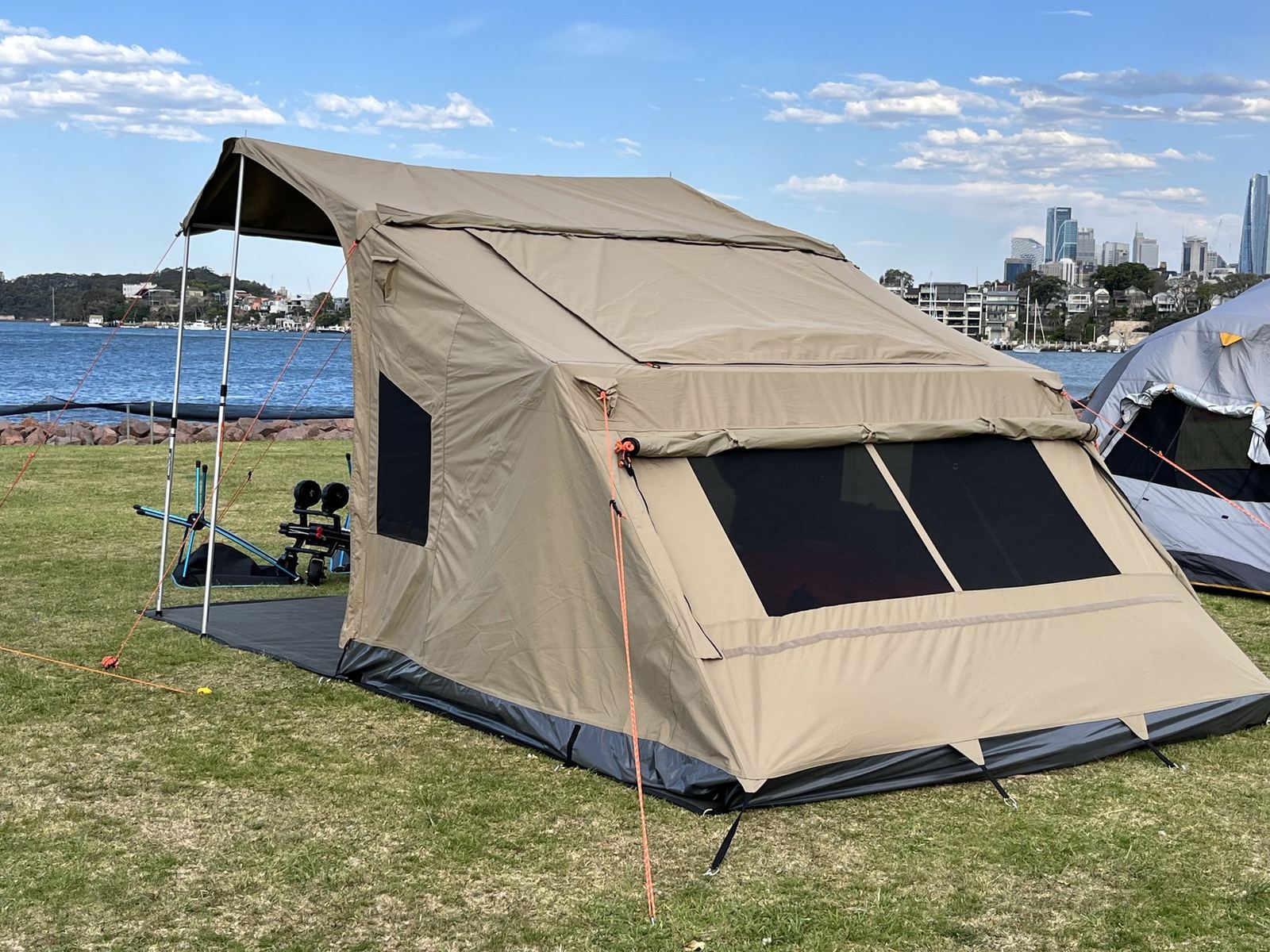 The same tent from the other side, city towers visible across the water beyond the campground