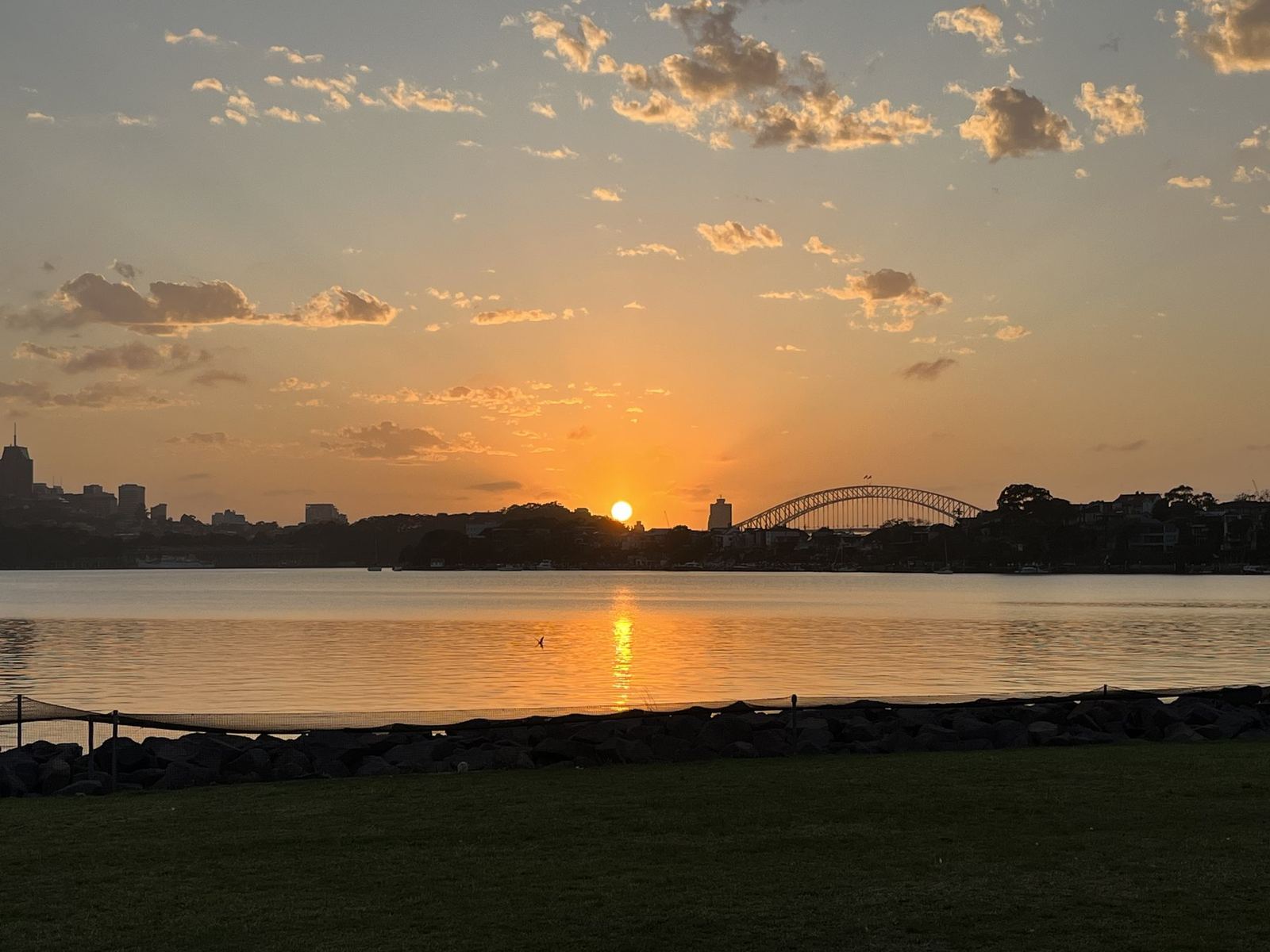 Sunrise over Sydney Harbour, the sun clearing the horizon beside the Harbour Bridge, its light laid down the water