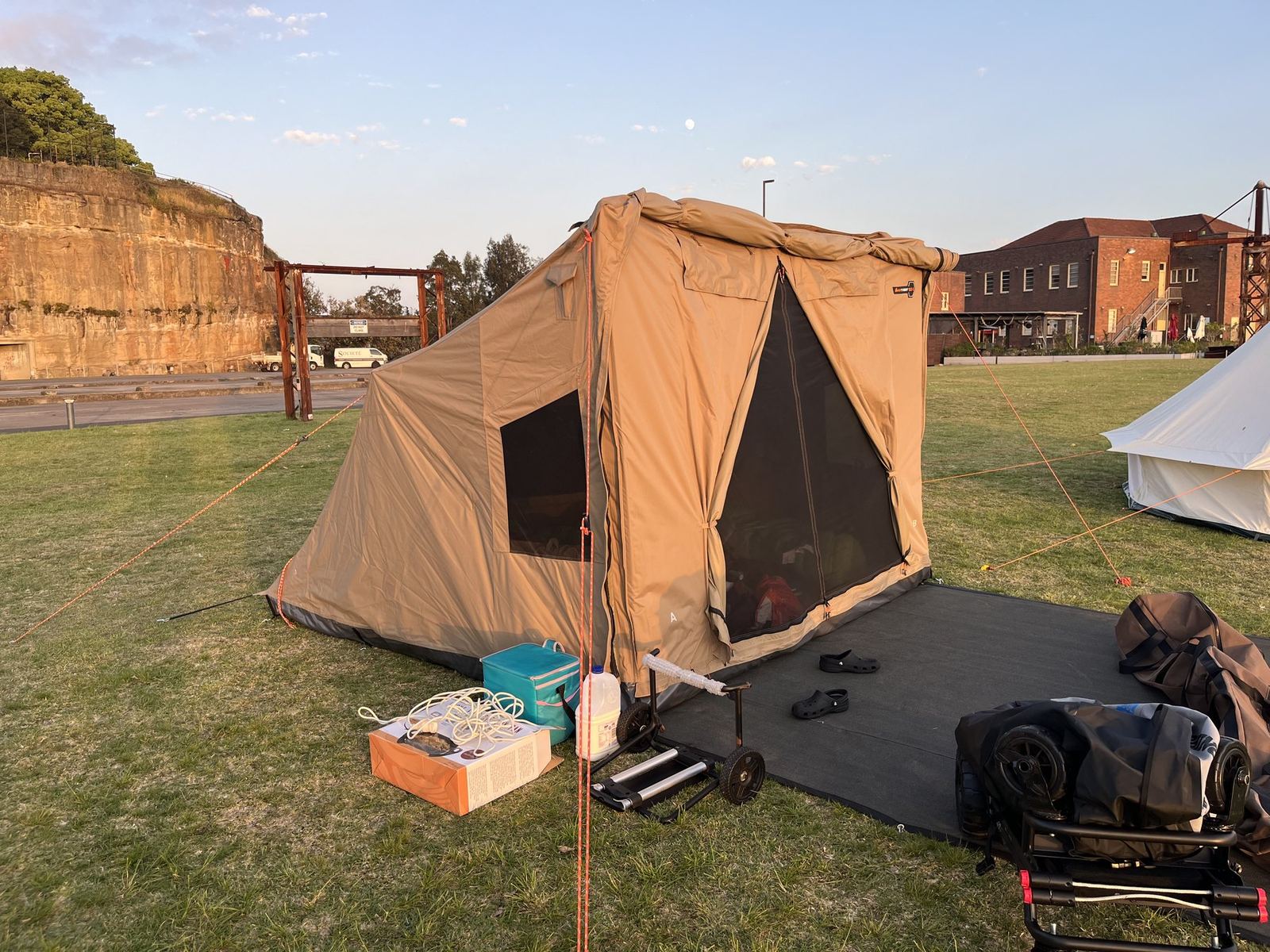 The tent lit gold by early sun against the island's cut sandstone wall and old industrial buildings