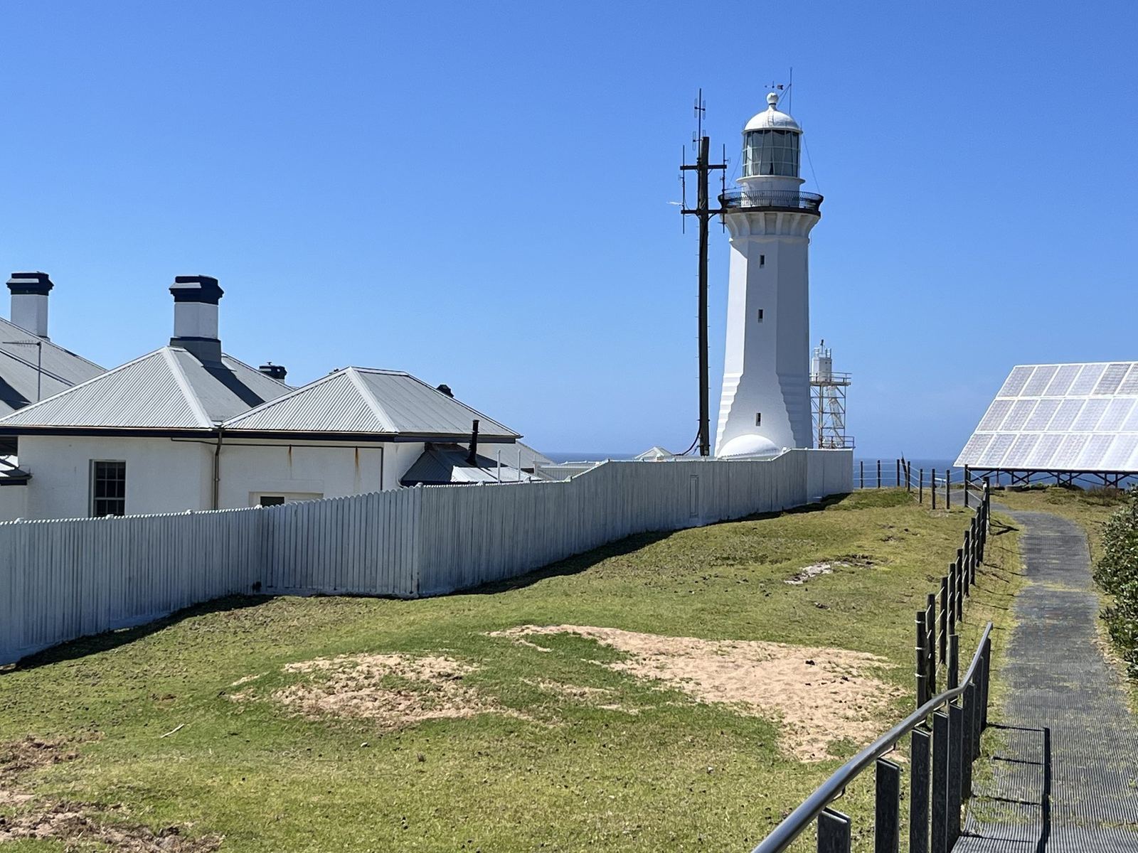 The lighthouse beyond the white keepers' cottages and their fenced yards on the headland
