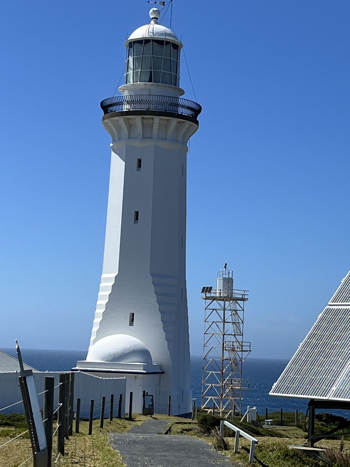 Green Cape lighthouse, a tall white tapered tower, standing against a clear blue sky