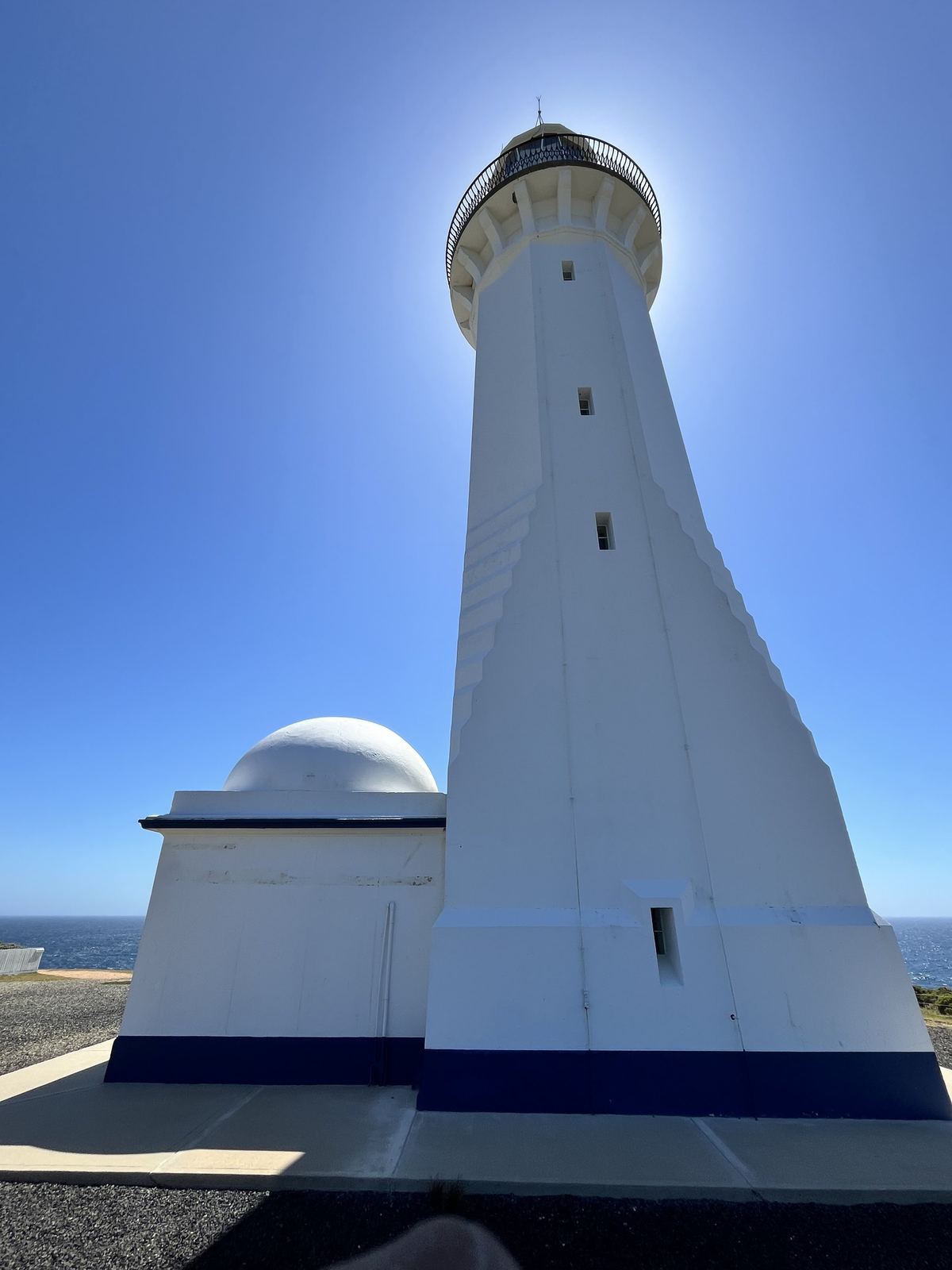 The lighthouse tower photographed from its base looking up, its gallery and lantern room against the sky