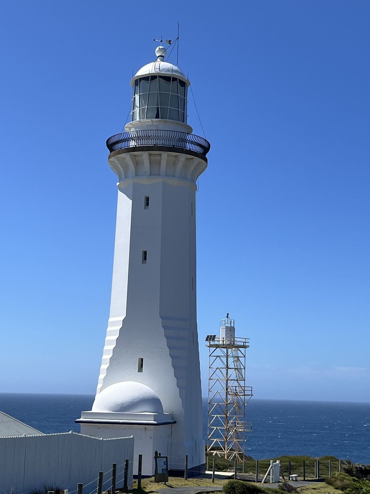 The lighthouse with open ocean behind it, the horizon high in the frame