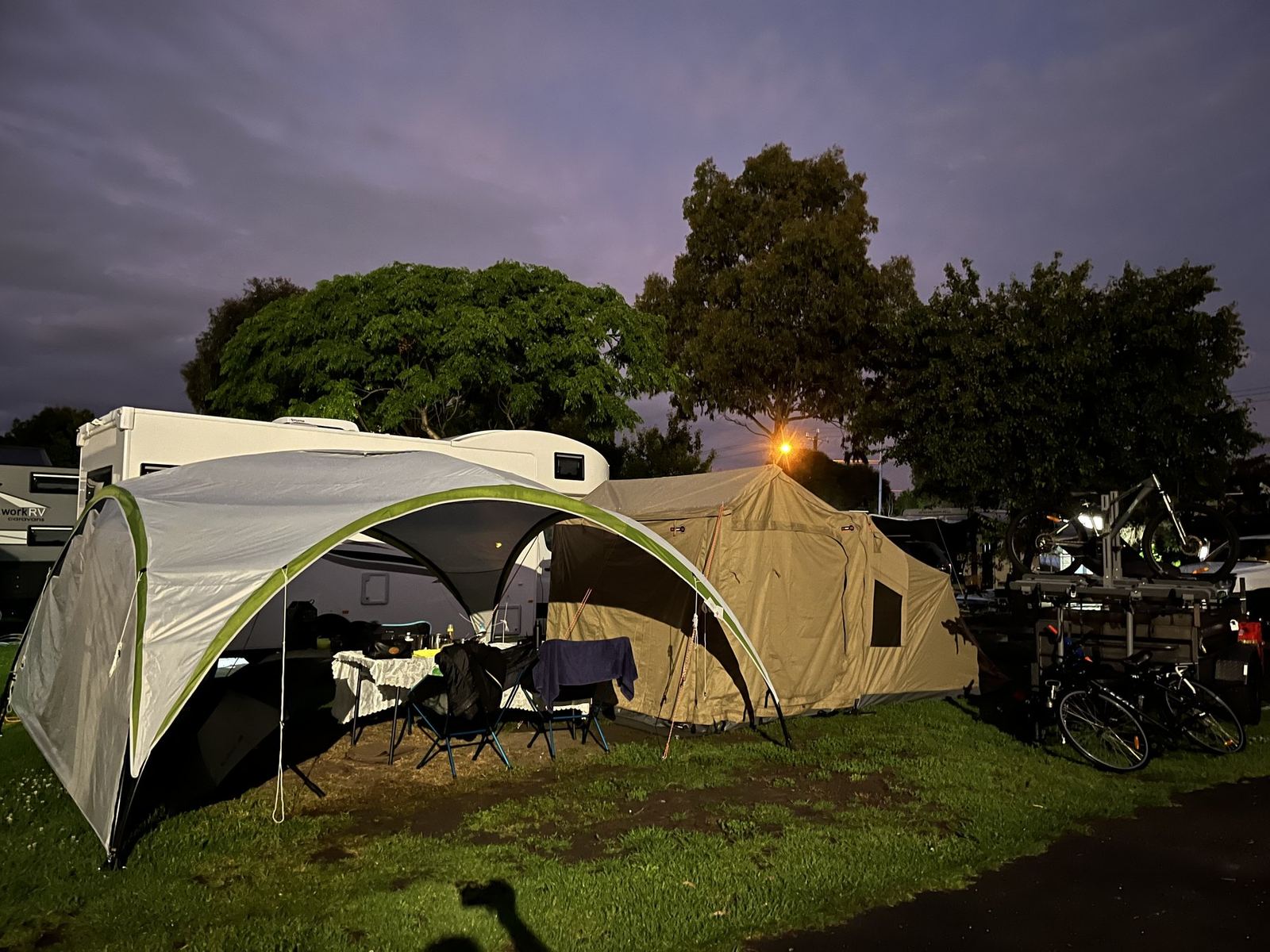 The same camp a moment later from further back, bikes and trailer alongside, vans on the neighbouring sites