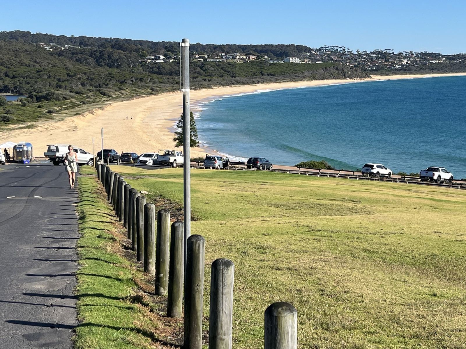 The same bay a few seconds later, looking along the beach towards houses on the headland, someone walking up the road in the foreground