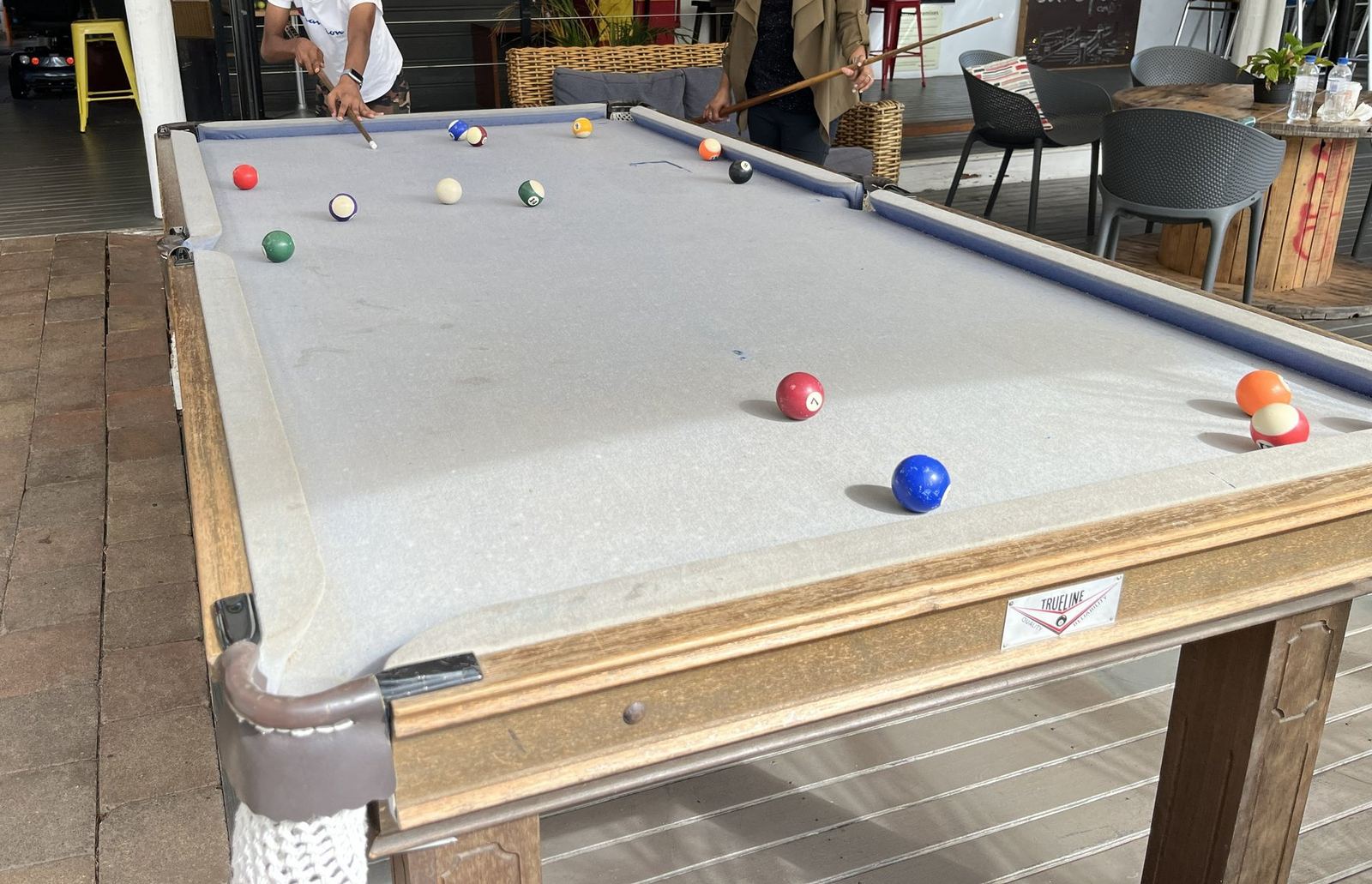 A pool table mid-game in the park's open-sided games room, balls scattered across the felt