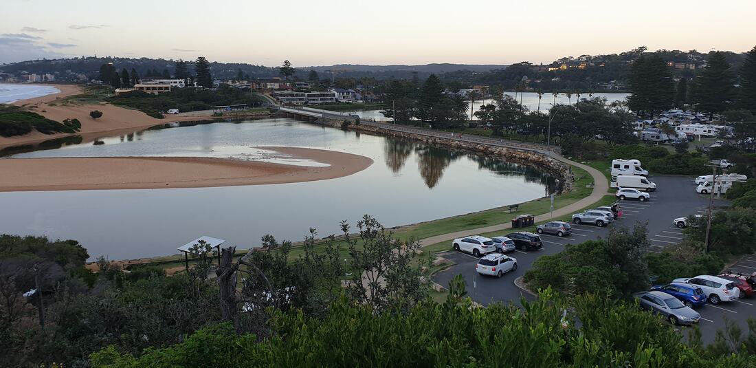 View from North Narrabeen Headland over Narrabeen Lagoon, the sandbar and the caravans of the holiday park below