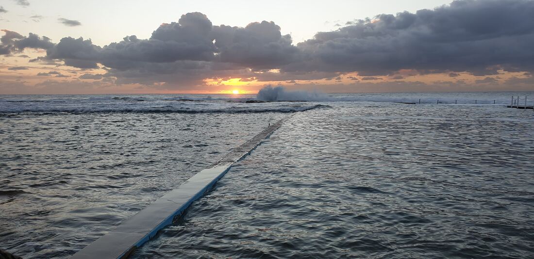 North Narrabeen ocean pool at dawn with the sun just above the horizon