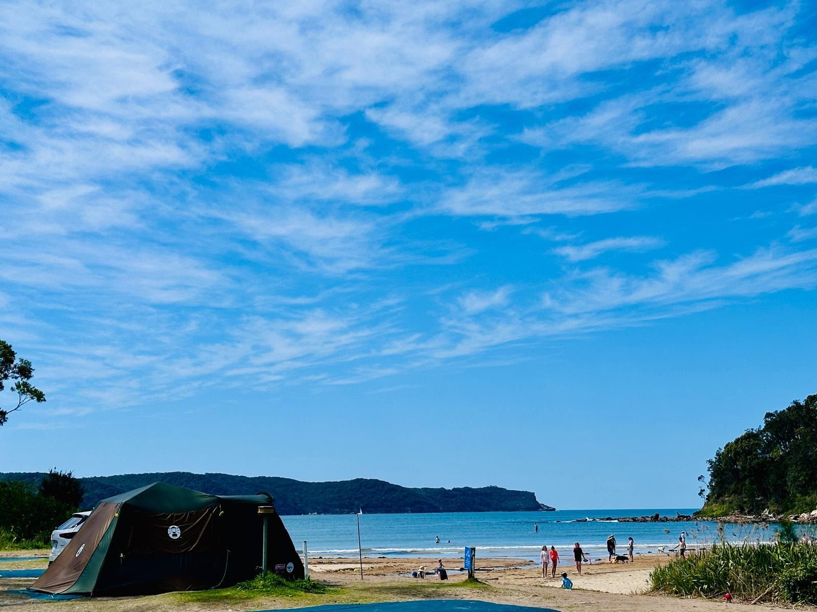 The same outlook a little wider, showing the beach, swimmers in the shallows and the far point