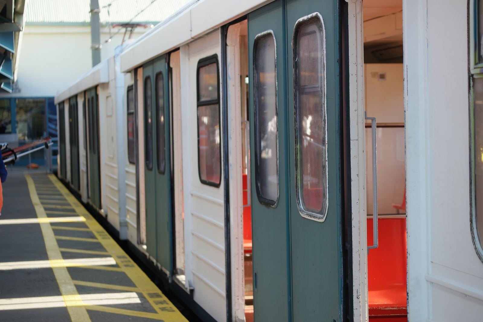 A green and cream Skitube carriage standing at the platform with its doors open