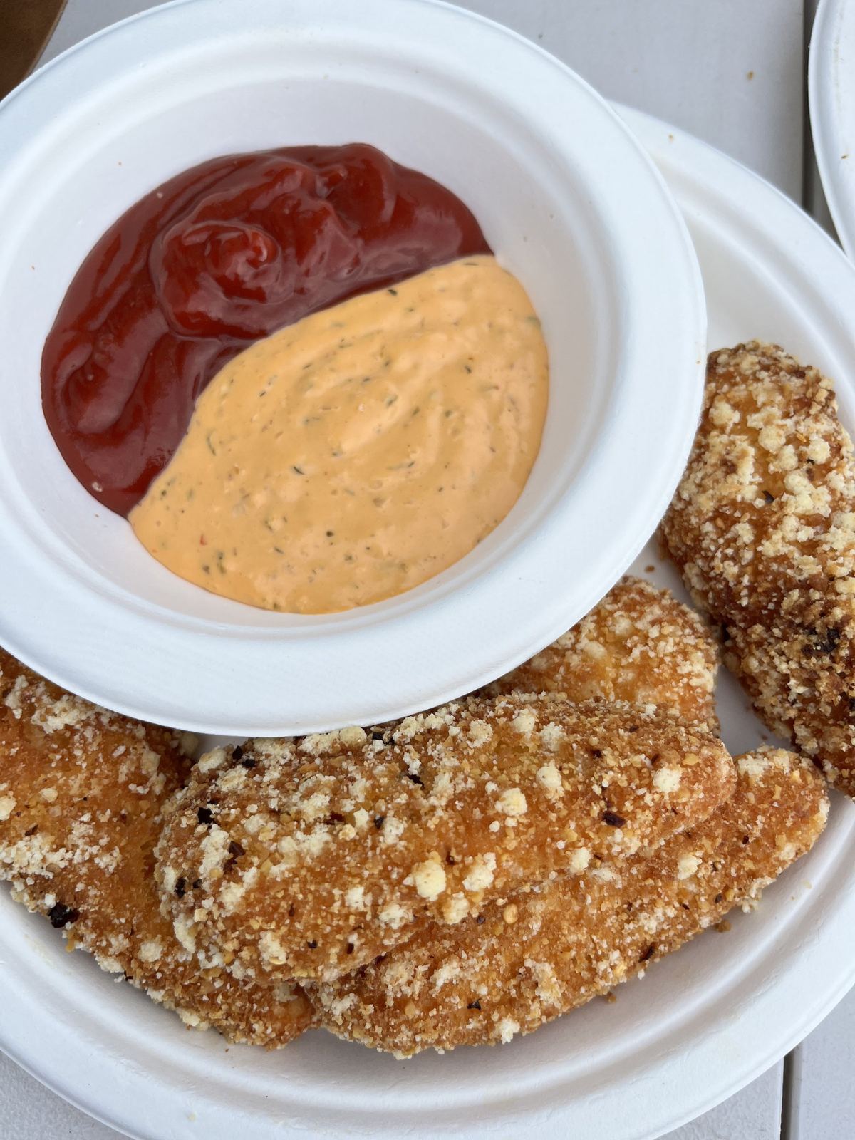 A closer view of the same plate, tomato sauce and a creamy sauce in a bowl beside the cutlet